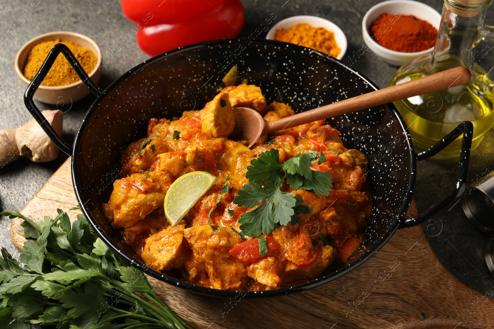 Photo of Delicious chicken curry and ingredients on grey table