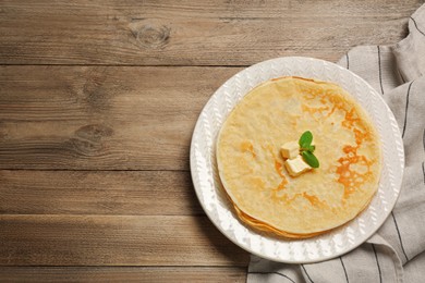 Photo of Stack of delicious crepes with melting butter and mint on wooden table, top view. Space for text