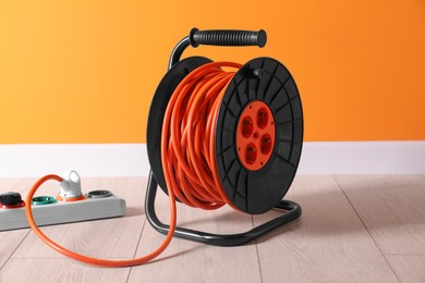 Photo of Extension cord reel plugged into socket on white floor indoors. Electrician's equipment