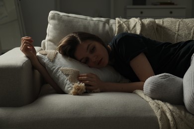 Photo of Sad young woman lying on sofa at home