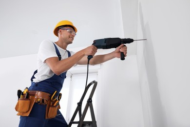 Photo of Worker using electric drill indoors, low angle view
