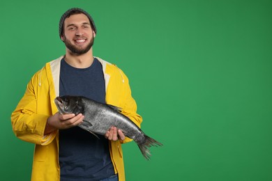 Photo of Fisherman with caught fish on green background, space for text