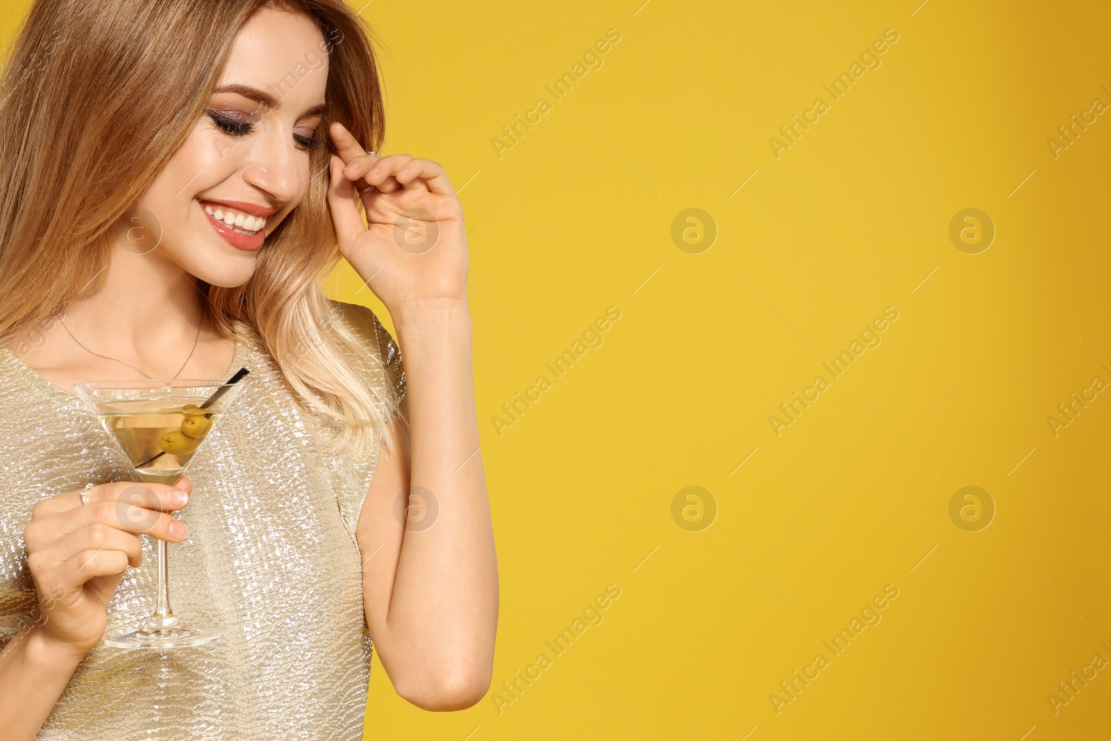 Photo of Beautiful young woman with glass of martini cocktail on color background, space for text