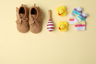Photo of Flat lay composition with child's booties and toys on beige background, space for text