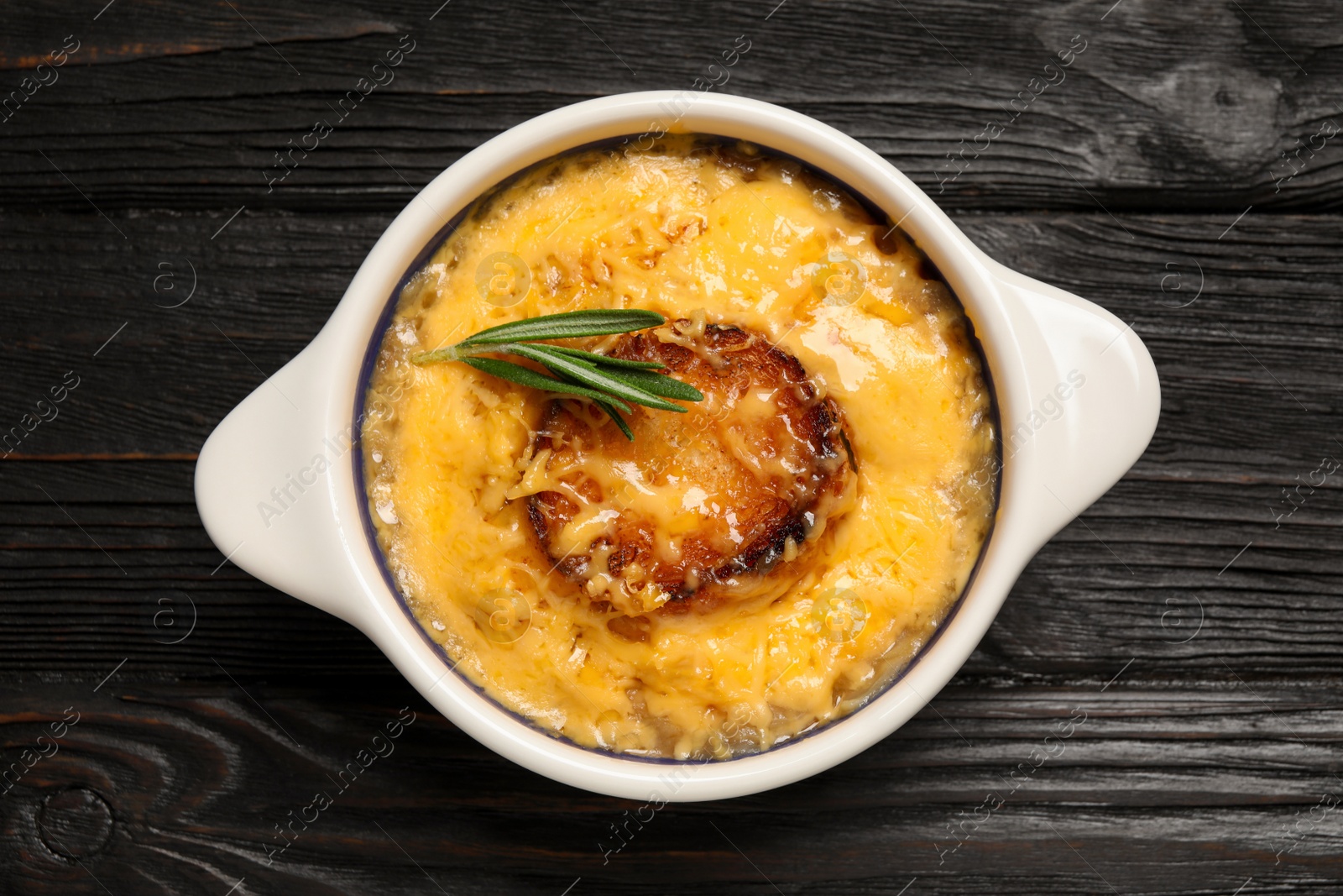 Photo of Tasty homemade french onion soup on black wooden table, top view