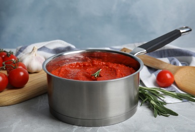 Photo of Delicious tomato sauce in pan on marble table