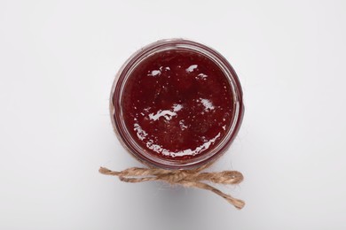 Photo of Tasty canned raspberry jam on white background, top view