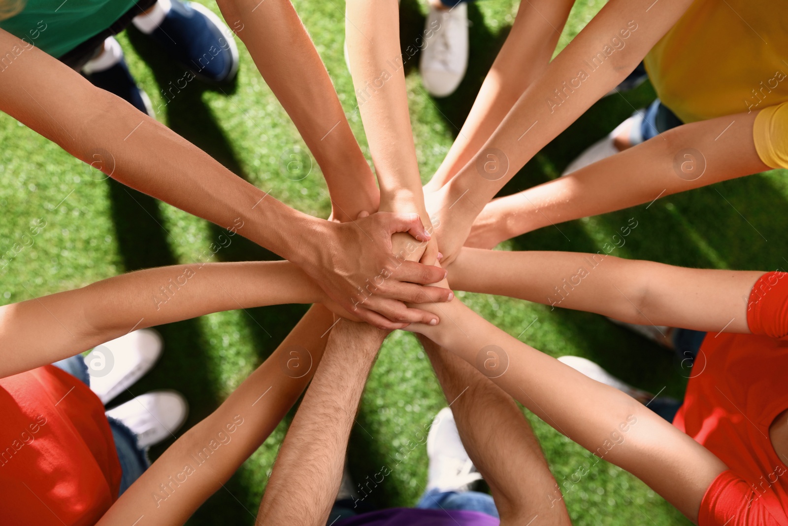 Photo of Group of volunteers joining hands together outdoors, top view