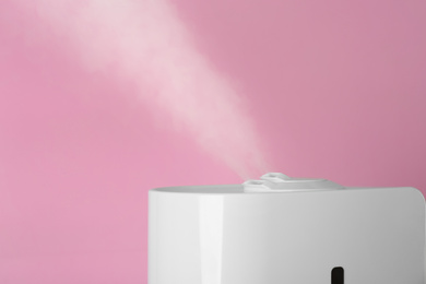 Photo of Modern air humidifier on pink background, closeup. Space for text