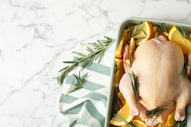 Flat lay composition with chicken, orange slices, rosemary and kitchen towel on white marble table