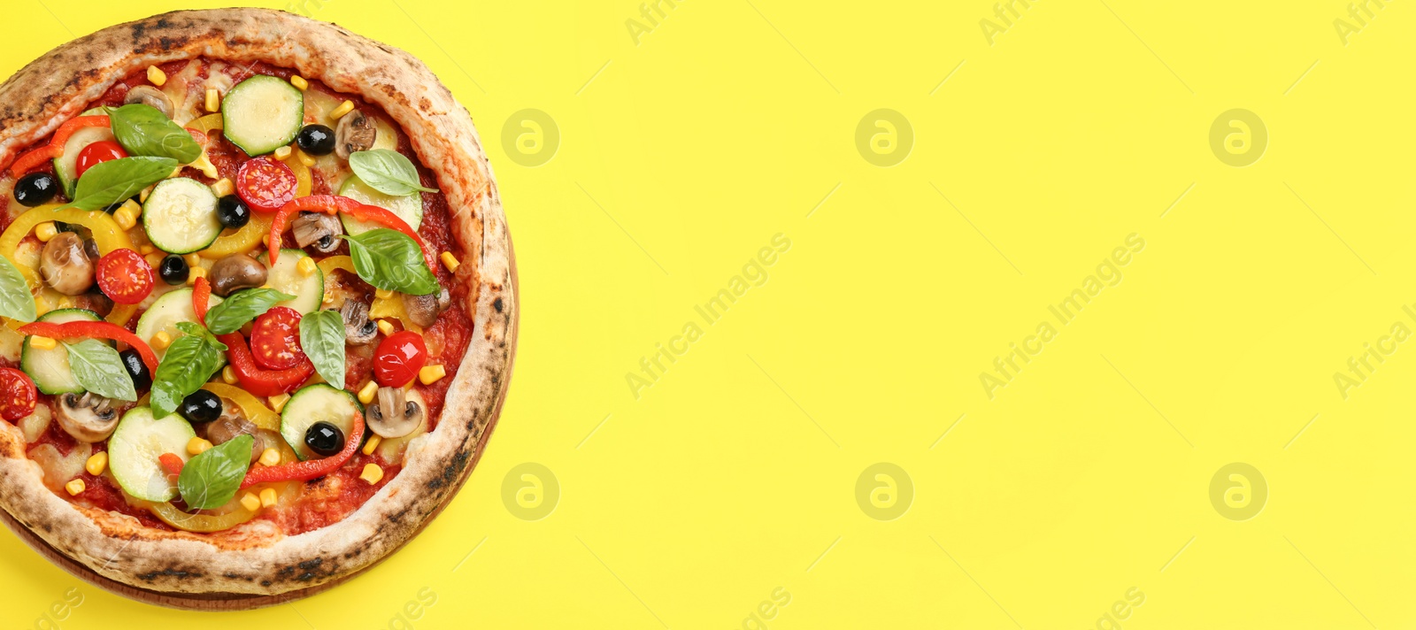 Photo of Delicious hot vegetable pizza on yellow background, top view. Space for text