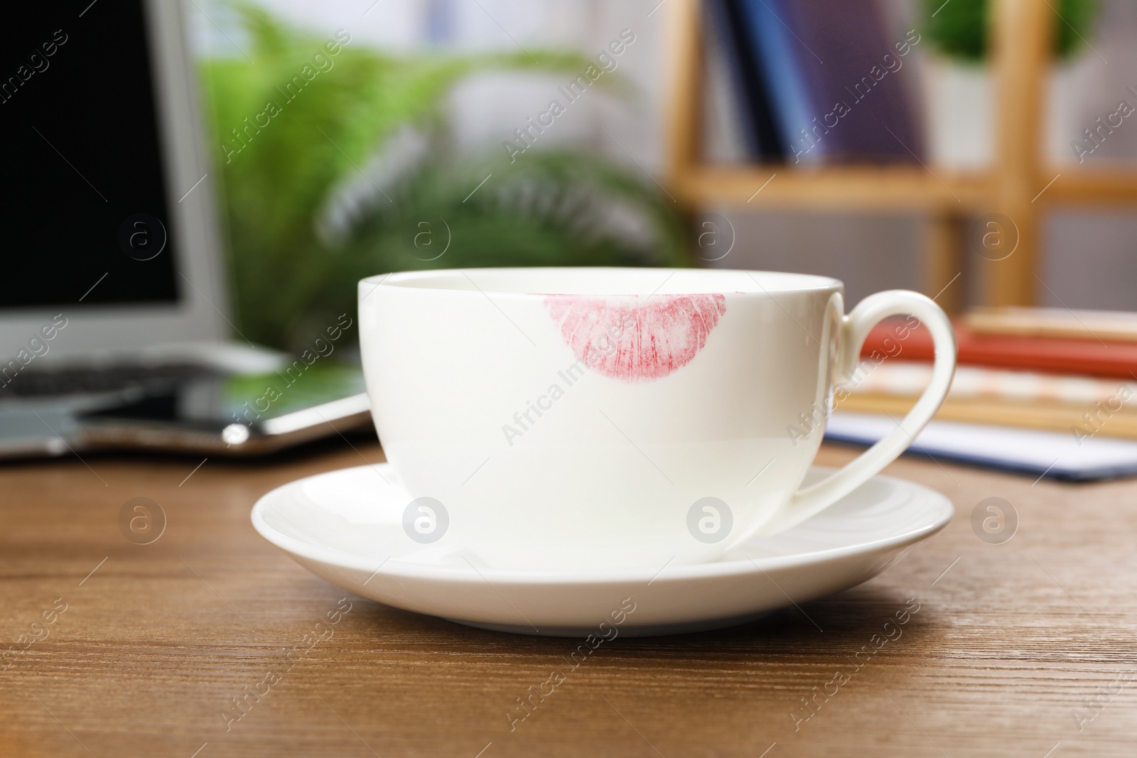 Photo of Ceramic cup with lipstick mark on table at workplace