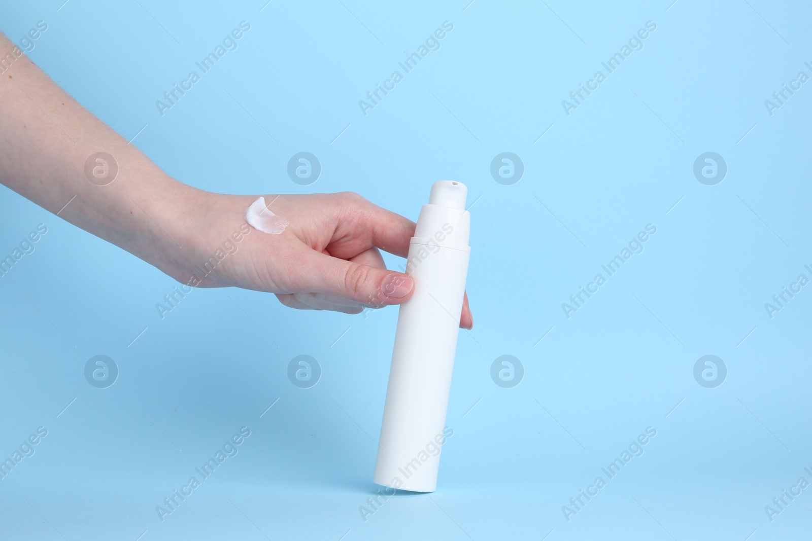 Photo of Woman with cream on light blue background, closeup