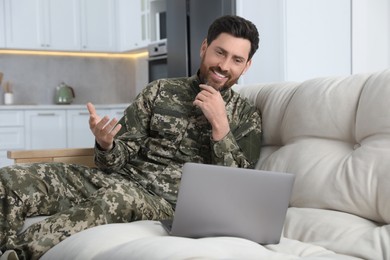 Photo of Happy soldier using video chat on laptop at home. Military service