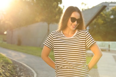 Beautiful smiling woman in sunglasses outdoors, space for text