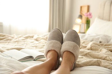 Woman wearing soft comfortable slippers on bed at home, closeup