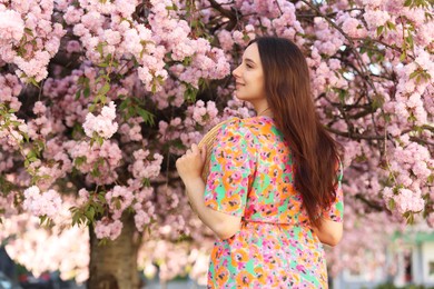 Photo of Beautiful woman with straw hat near blossoming tree on spring day