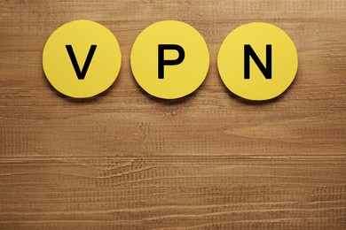 Paper notes with acronym VPN on wooden table, flat lay. Space for text