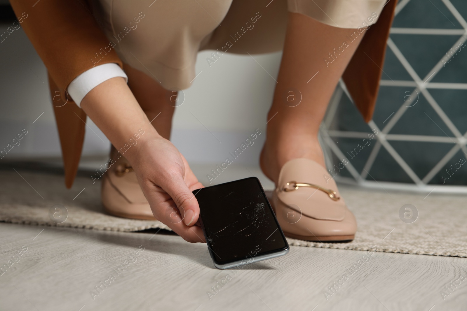 Photo of Woman taking damaged smartphone from floor, closeup. Device repairing