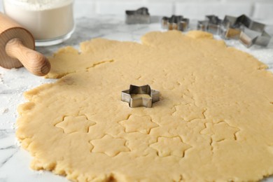 Making shortcrust pastry. Raw dough, cookie cutters and rolling pin on white marble table