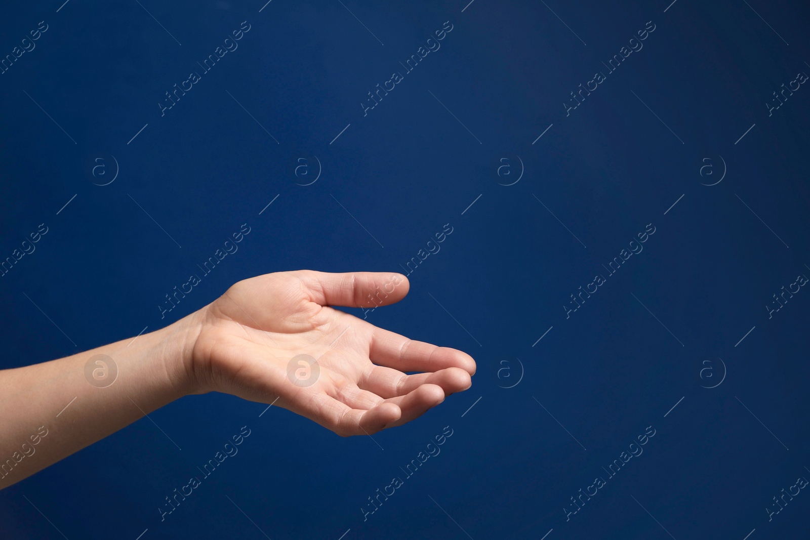 Photo of Woman holding something in hand on blue background, closeup. Space for text