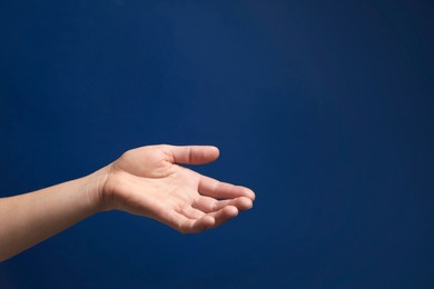 Woman holding something in hand on blue background, closeup. Space for text