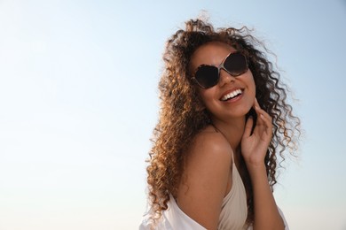 Photo of Beautiful African American woman with sunglasses against blue sky. Sun protection care
