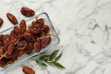 Photo of Tasty sweet dried dates on white marble table, flat lay. Space for text