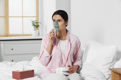 Photo of Sick young woman using nebulizer on bed at home