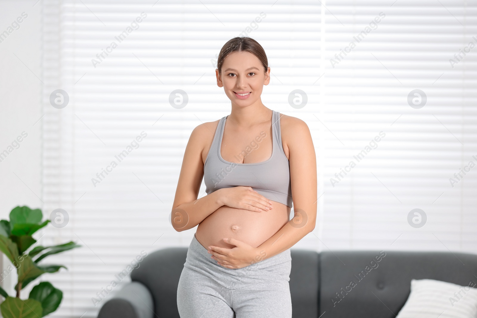 Photo of Beautiful pregnant woman standing near sofa at home