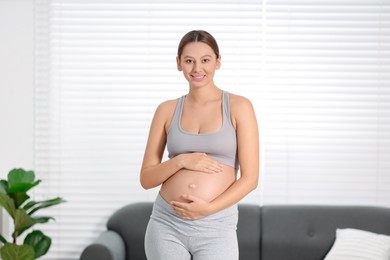 Photo of Beautiful pregnant woman standing near sofa at home