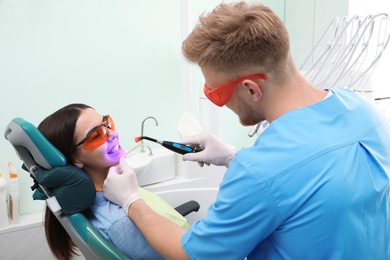 Photo of Professional dentist working with patient in modern clinic. Teeth whitening