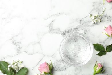 Photo of Flat lay composition with cosmetic gel and beautiful flowers on white marble table. Space for text