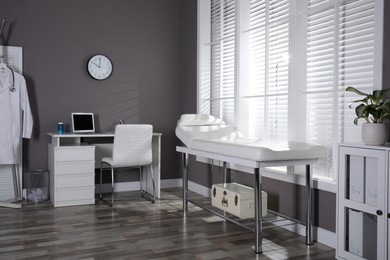 Photo of Modern medical office interior with doctor's workplace and examination table