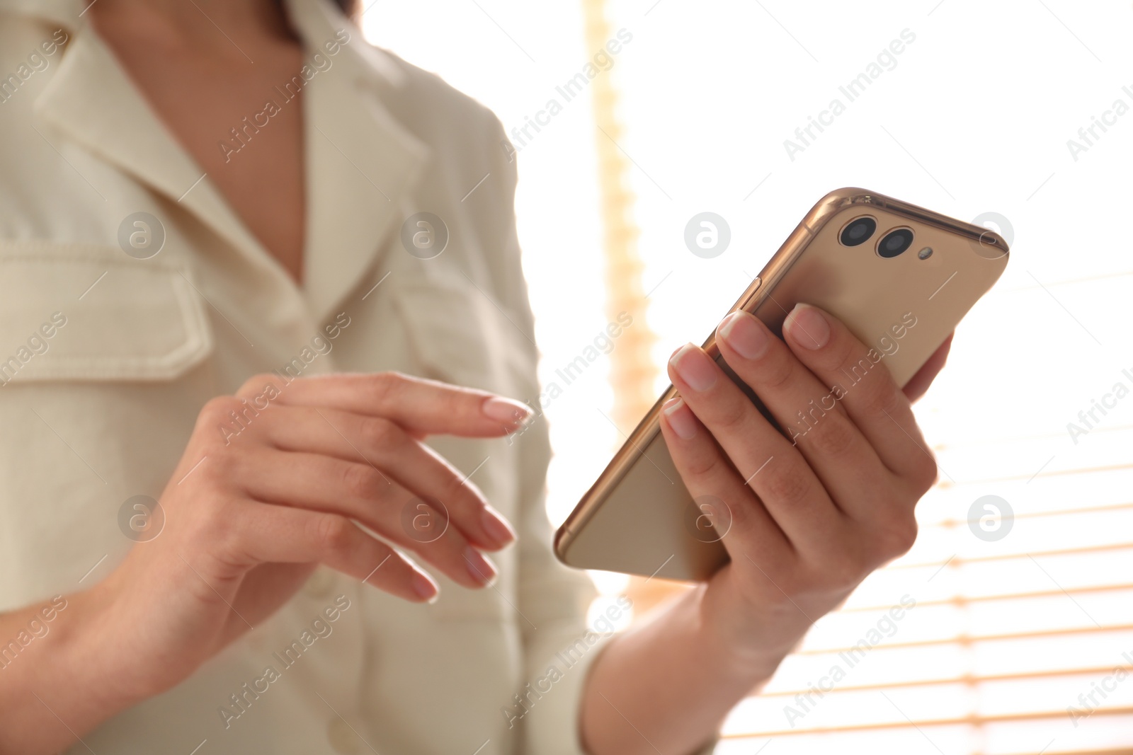 Photo of Young woman using modern smartphone indoors, closeup