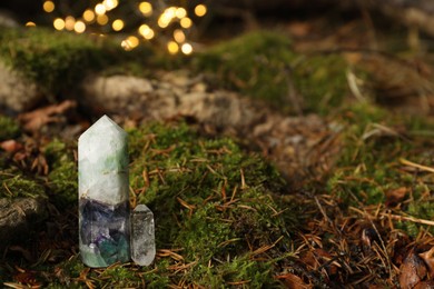 Photo of Crystals on moss against blurred lights, space for text