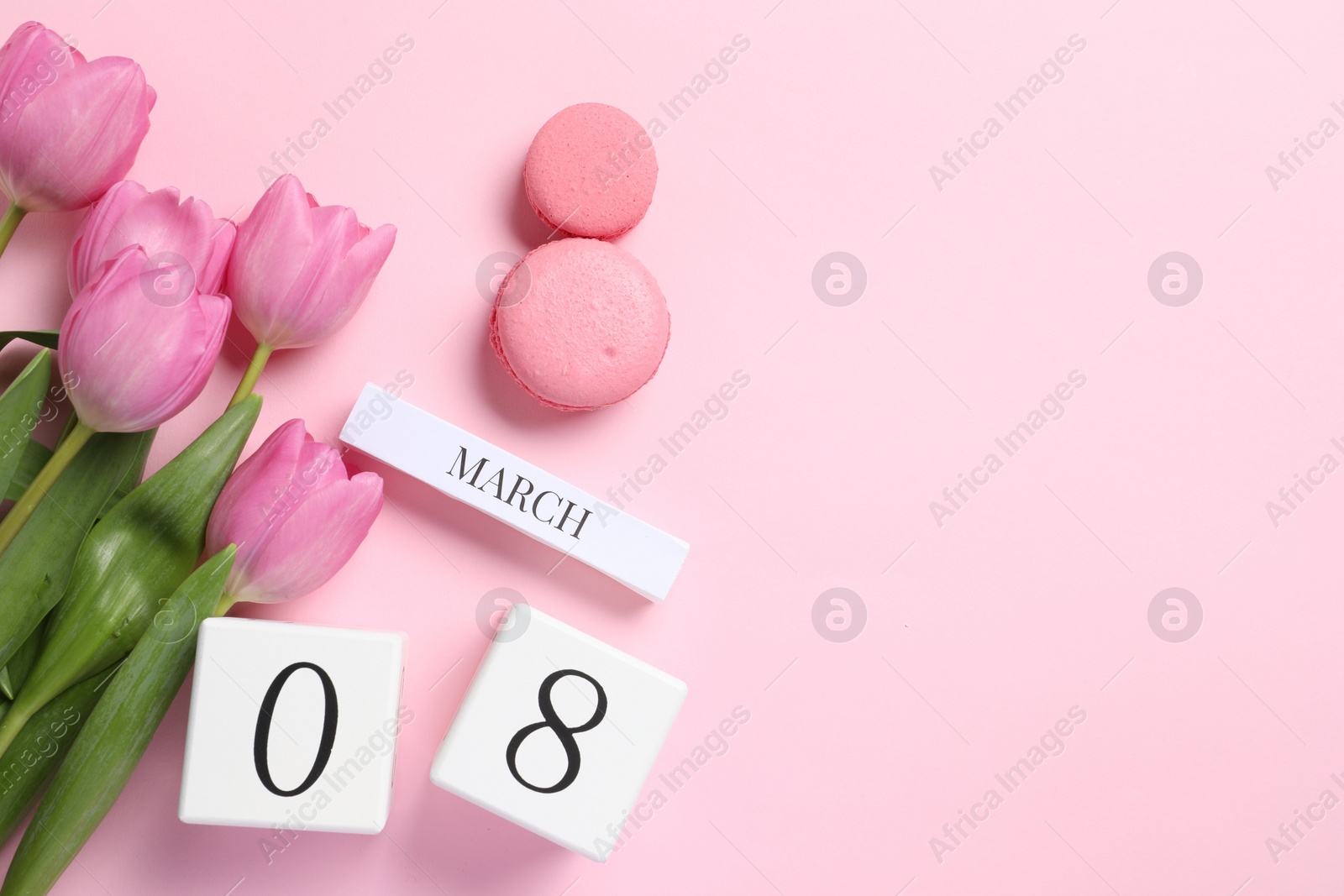 Photo of International Women's day - 8th of March. Macaron cookies, wooden block calendar and beautiful flowers on pink background, flat lay. Space for text