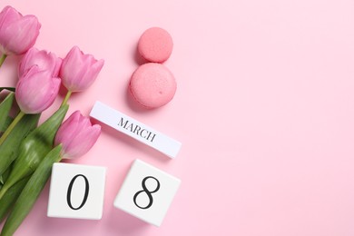 Photo of International Women's day - 8th of March. Macaron cookies, wooden block calendar and beautiful flowers on pink background, flat lay. Space for text