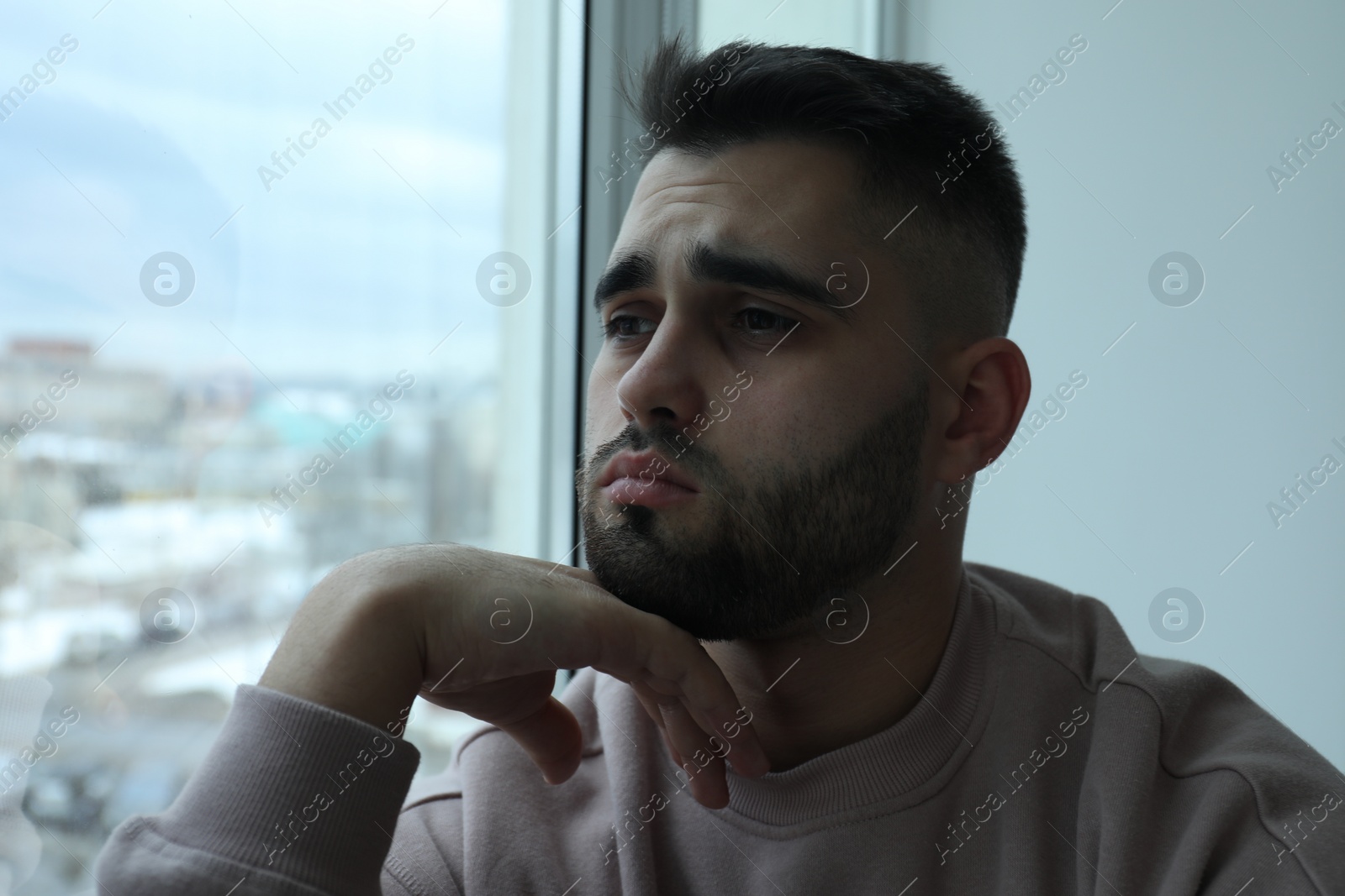 Photo of Portrait of sad man near window at home