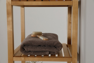 Shelving unit with toiletries near light wall indoors. Bathroom interior element