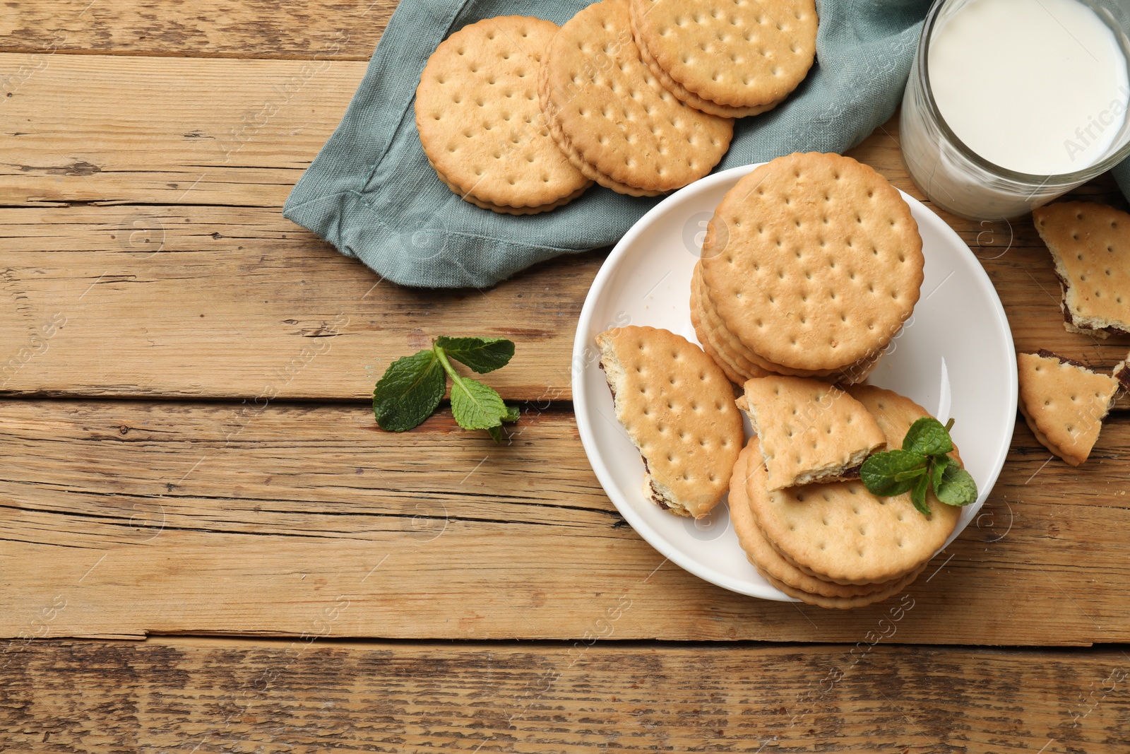 Photo of Tasty sandwich cookies and glass of milk on wooden table, flat lay. Space for text