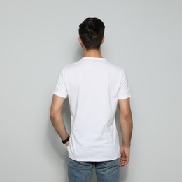 Young man in t-shirt on light background. Mock up for design