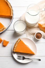 Flat lay composition with piece of fresh delicious homemade pumpkin pie on wooden background