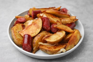 Photo of Delicious baked potato with thin dry smoked sausages and onion on gray table, closeup