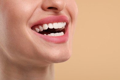 Woman with clean teeth smiling on beige background, closeup. Space for text