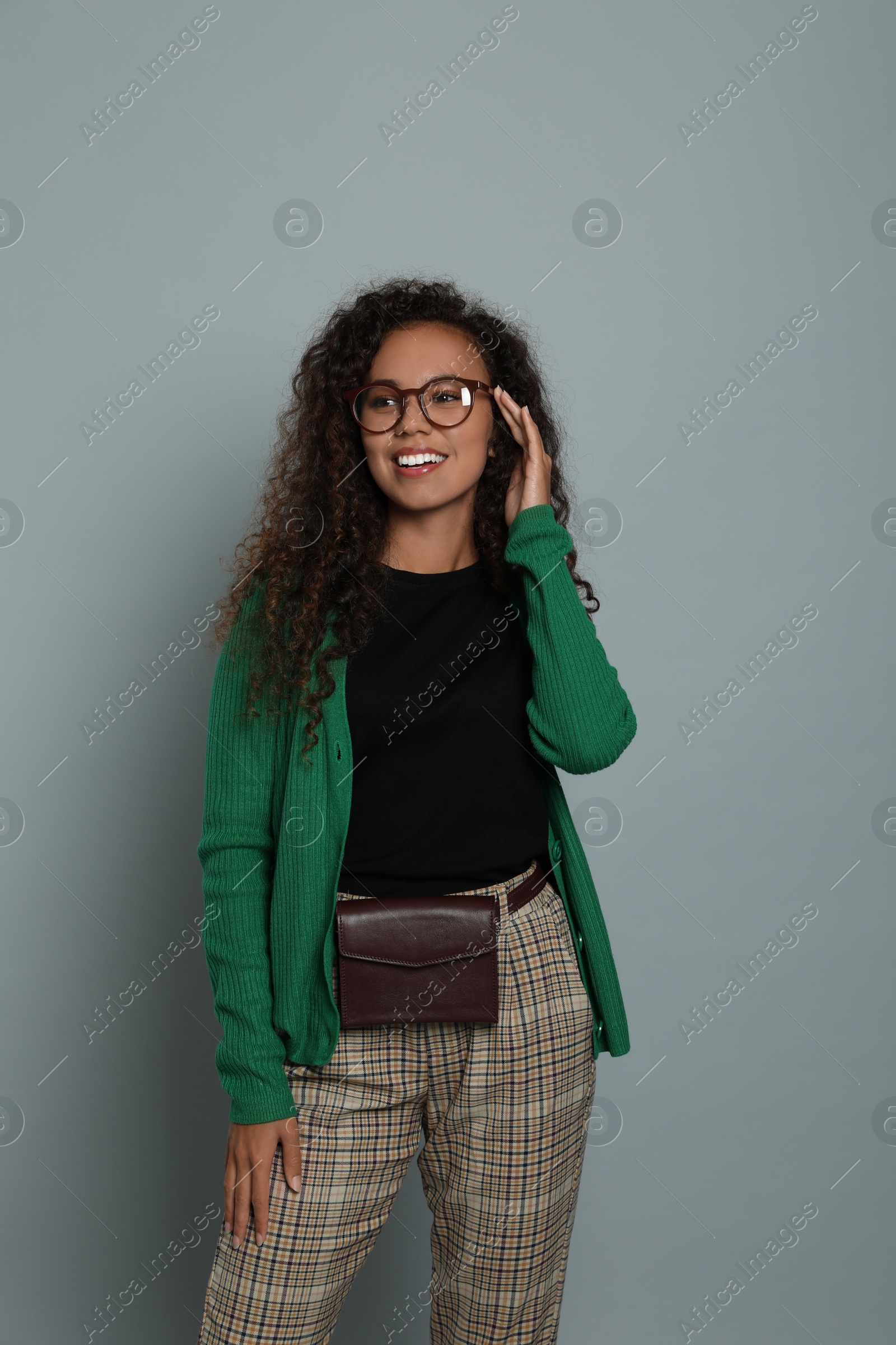 Photo of Beautiful African American woman with stylish waist bag on grey background