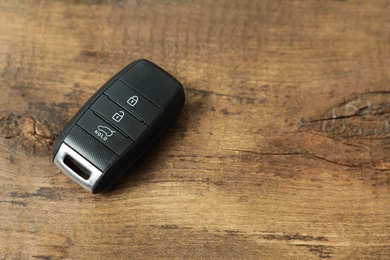 Photo of Remote car key on wooden background. Space for text