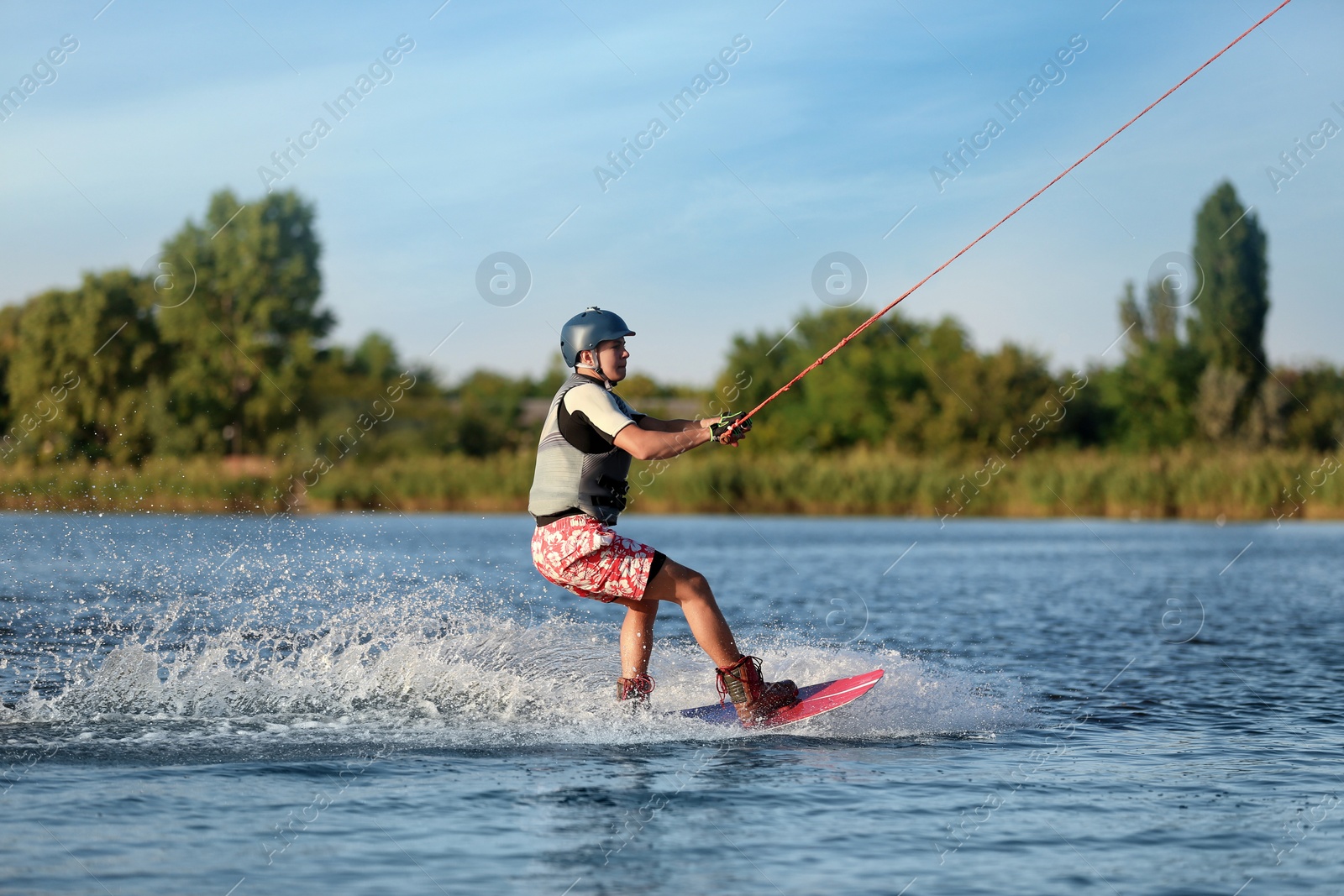 Photo of Teenage boy wakeboarding on river. Extreme water sport