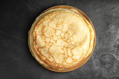 Photo of Stack of fresh thin pancakes on black table, top view