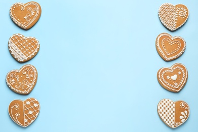 Gingerbread hearts decorated with icing on light blue background, flat lay. Space for text